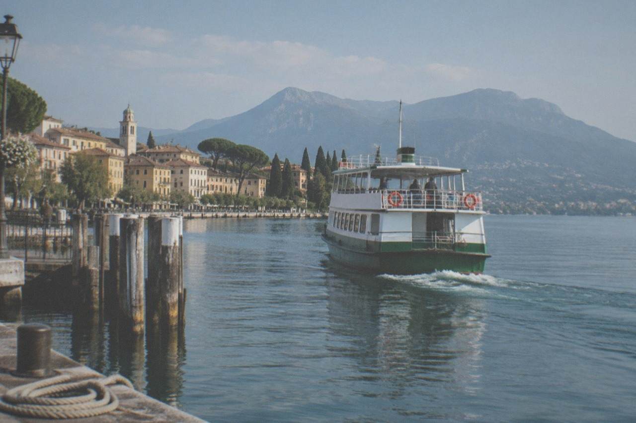 A passenger ferry crossing calm open water between two Lake Garda towns on a clear morning