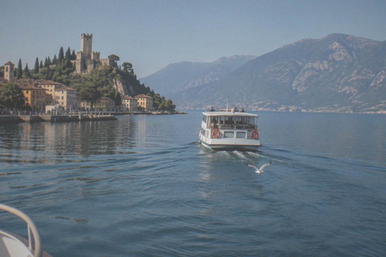 A passenger boat crossing open water between the shores of Malcesine and Limone sul Garda on Lake Garda