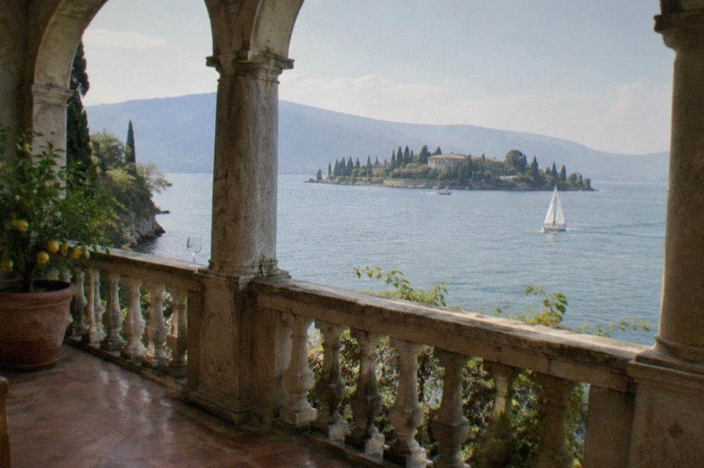 Close-up of the villa's loggia with arched windows and a view of the lake through the columns