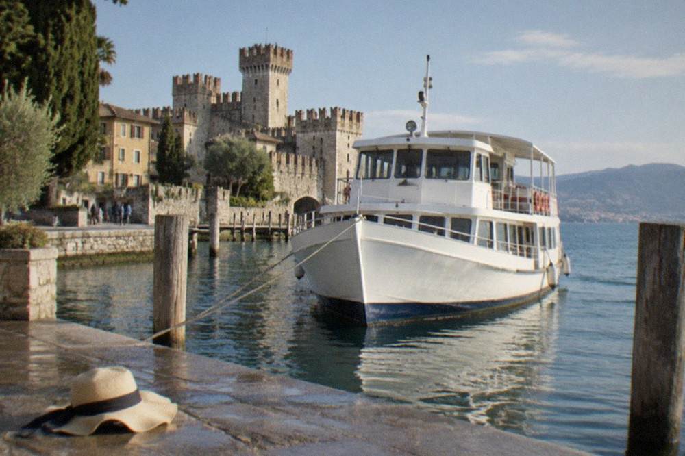 A public ferry moored at a stone pier with a walled old town behind it
