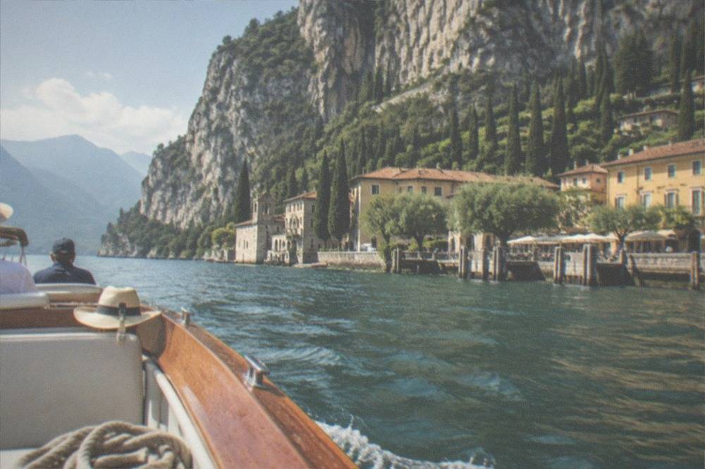 A small open tour boat passing a rocky cliff face above clear water