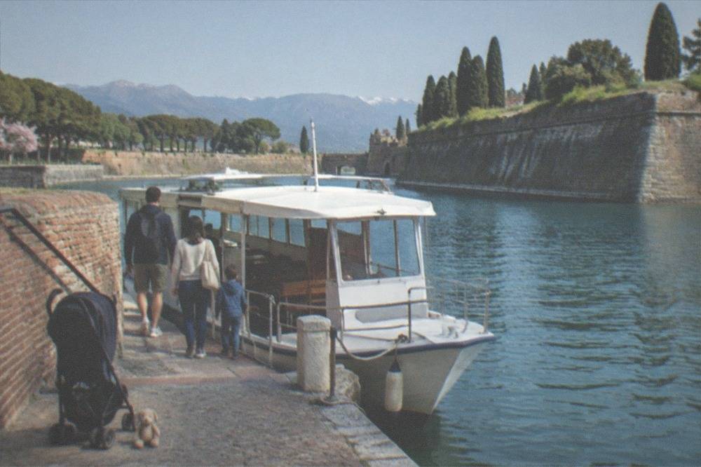A family boarding a small cruise boat at a lakeside pier in the morning