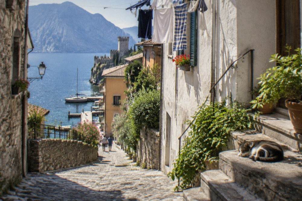 Narrow cobbled lane in Malcesine old town with stone buildings and a glimpse of the lake