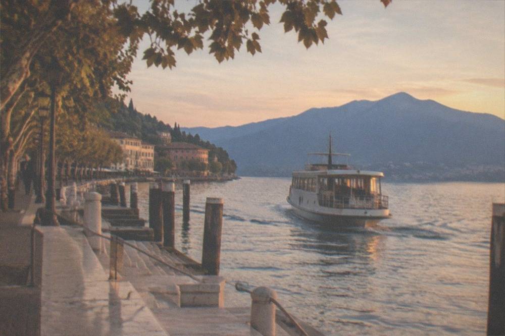 A passenger boat leaving a harbour at golden hour with mountains across the water