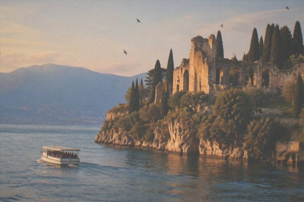 Small tour boat cruising close to a rocky headland in soft evening light