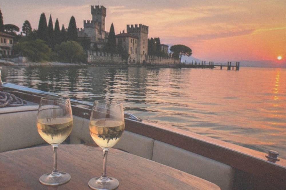 Two glasses of white wine on a small boat at sunset on Lake Garda