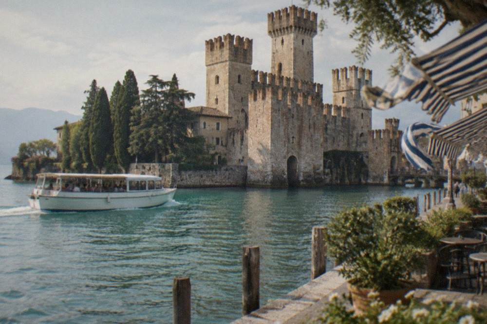 A shared tour boat passing a medieval castle that rises directly from the lake