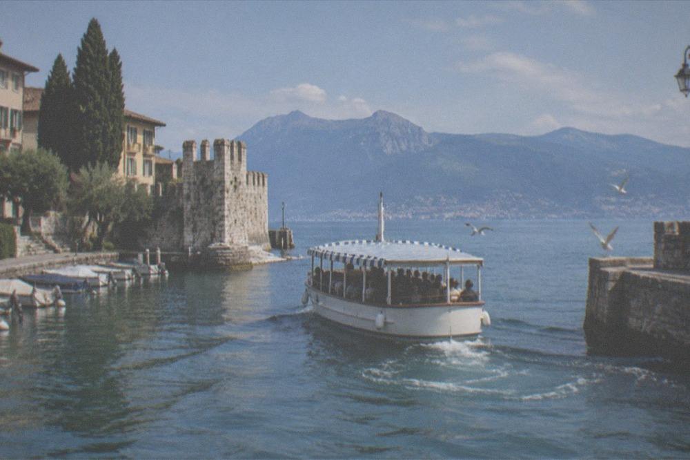 A tour boat leaving a harbour with passengers seated under an open canopy