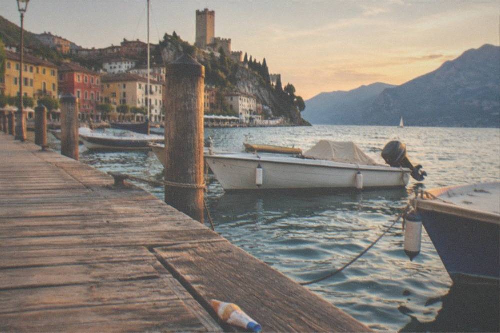 A wooden passenger pier at Malcesine with moored boats and clear evening light over the water