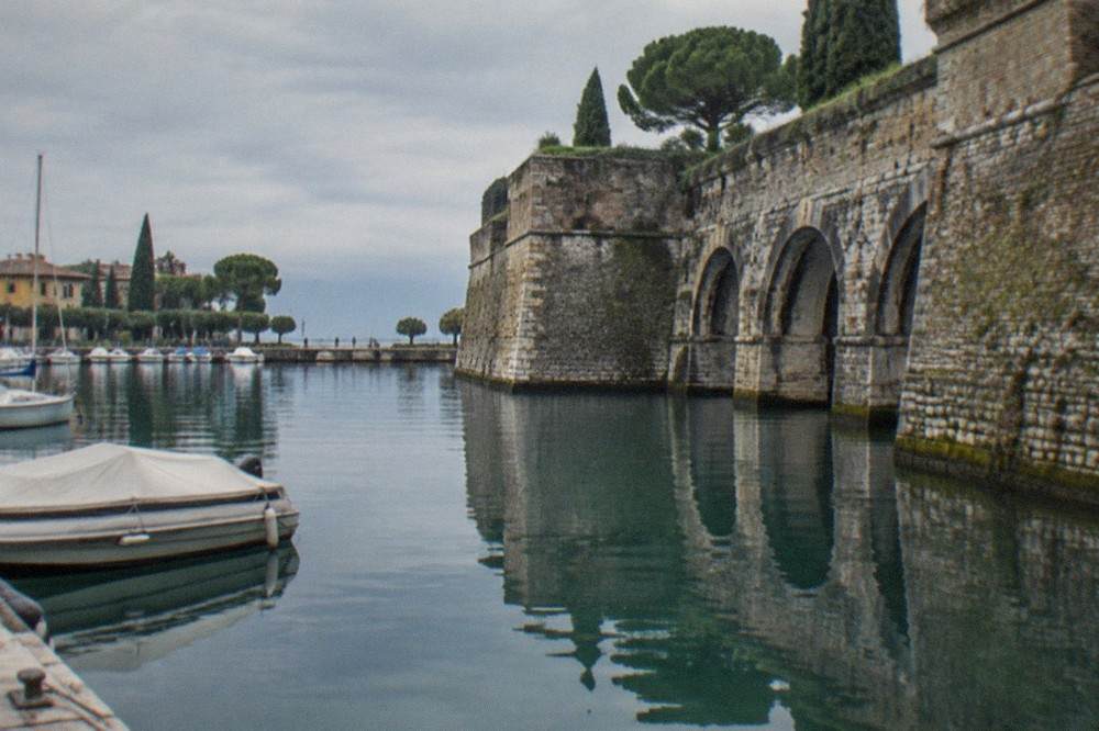 The arched walls of the Peschiera fortress reflected in the canal at the boat landing