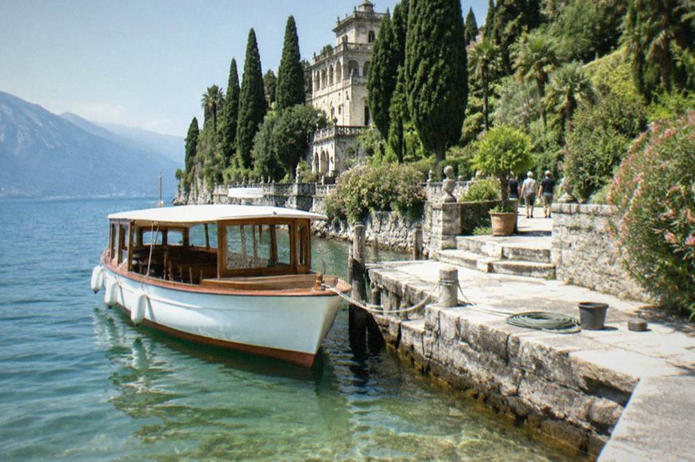 A stone landing stage with a small passenger boat tied up and clear water below