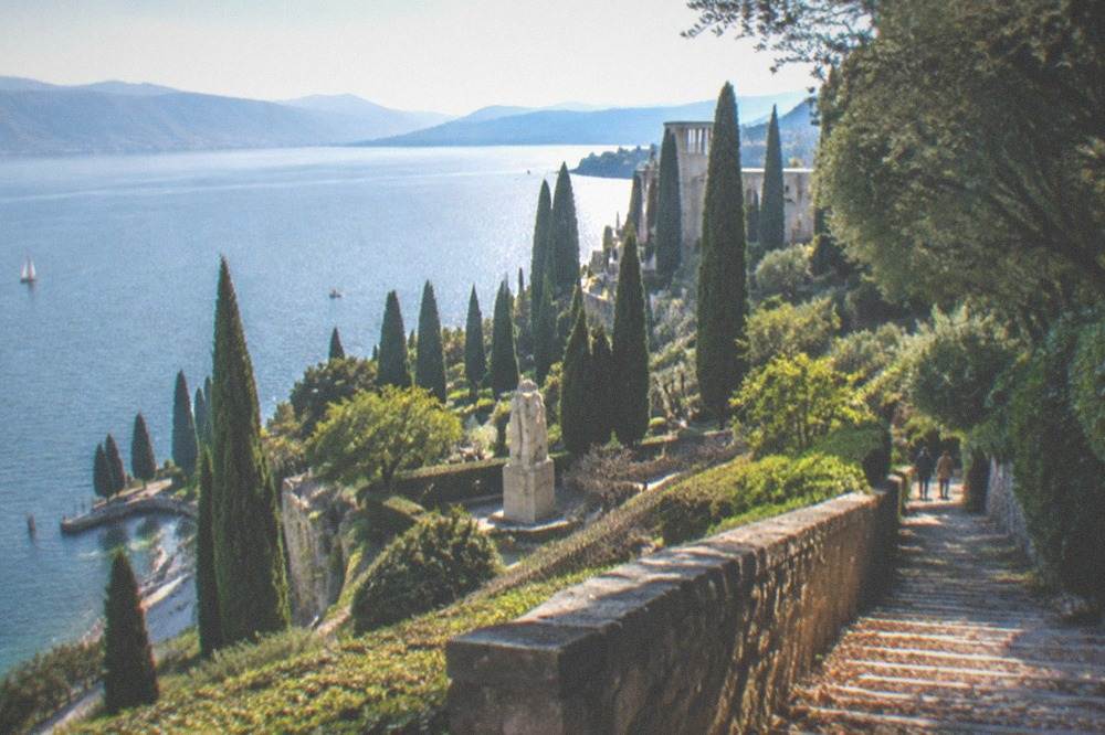A hillside estate with terraced gardens and tall cypress trees above a lakeside town