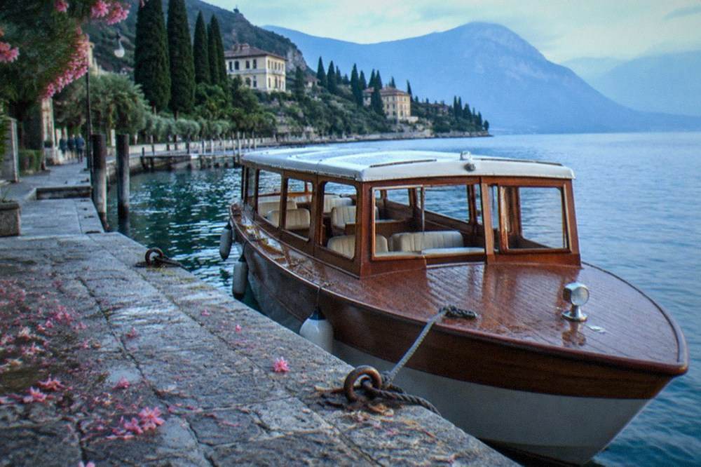 A stone jetty on a lake shore with a moored wooden passenger boat