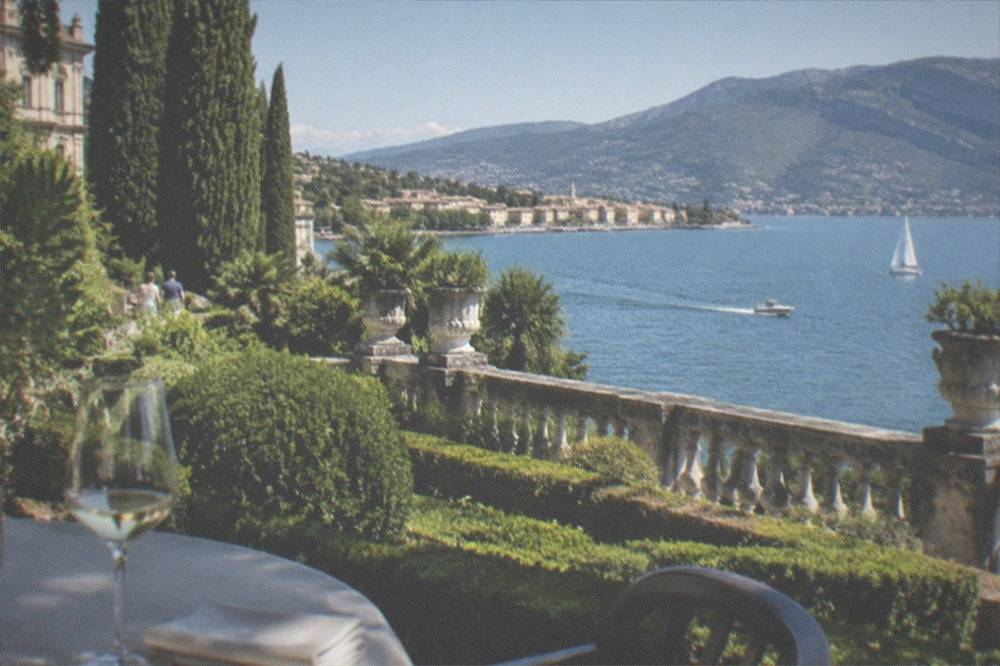 Formal terraced gardens with hedges and a stone balustrade above a lake