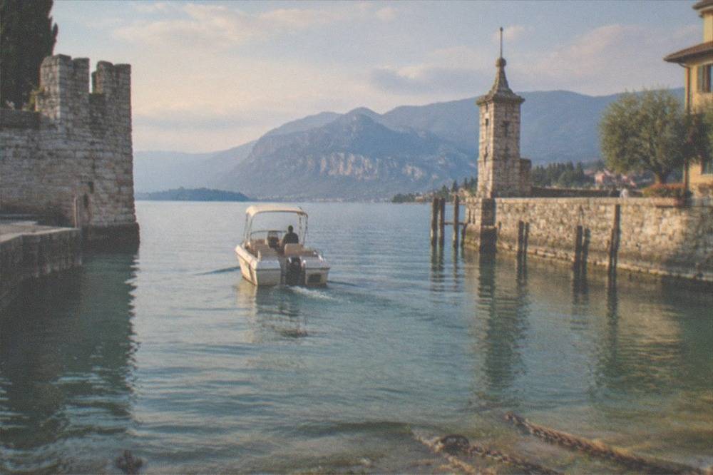 A motorboat slowing to enter a harbour between stone walls with clear water below