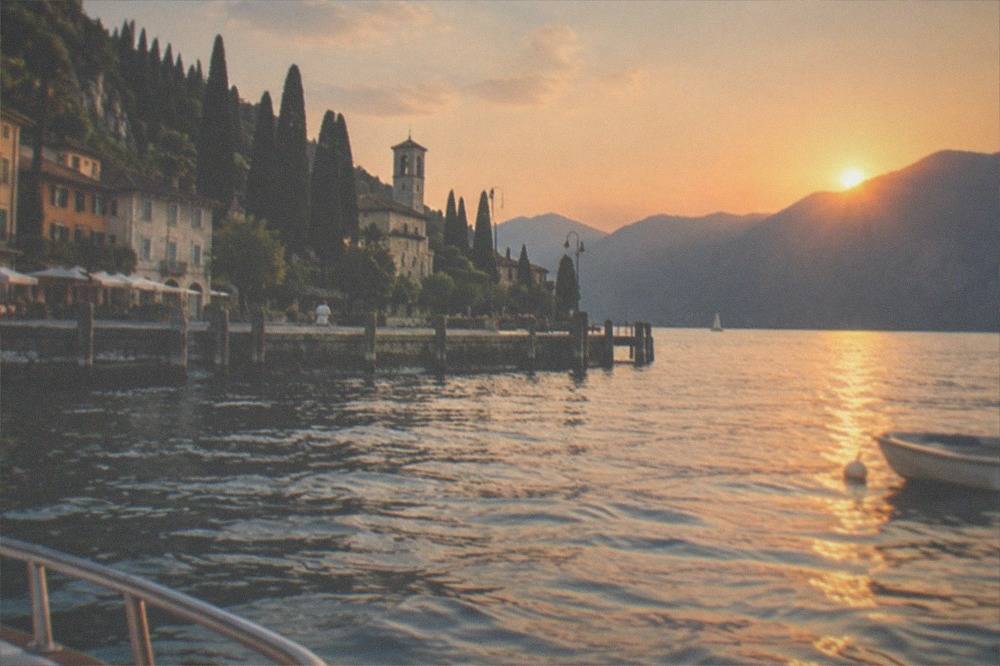 The sun setting behind the mountains on the western shore of Lake Garda seen from open water