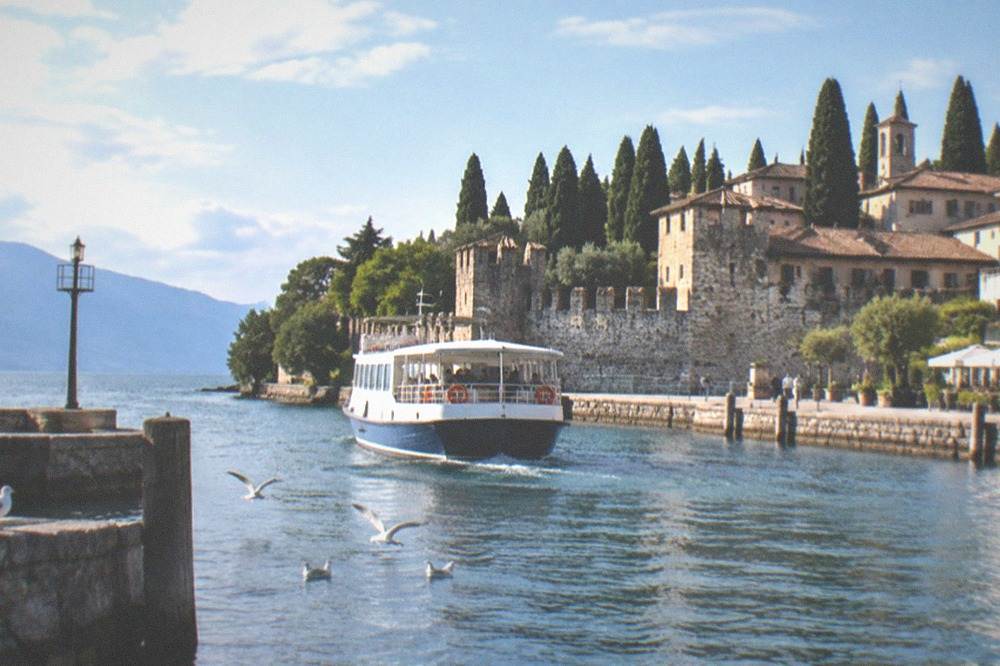 A ferry approaching a stone quay in a small Lake Garda harbour town