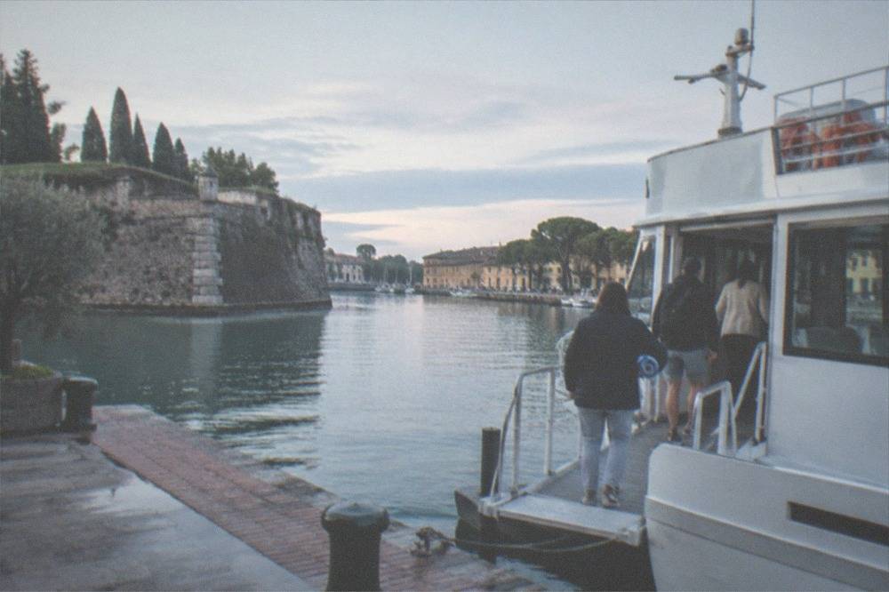 Passengers boarding a ferry at a lakeside landing stage in morning light