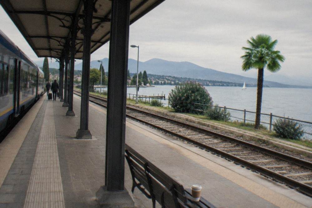 A regional train at Desenzano del Garda station with the lake visible beyond the platform