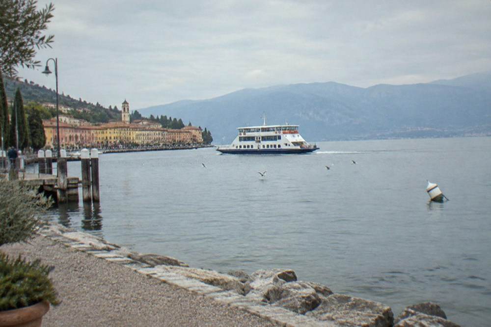A white Lake Garda ferry crossing calm water between small lakeside towns