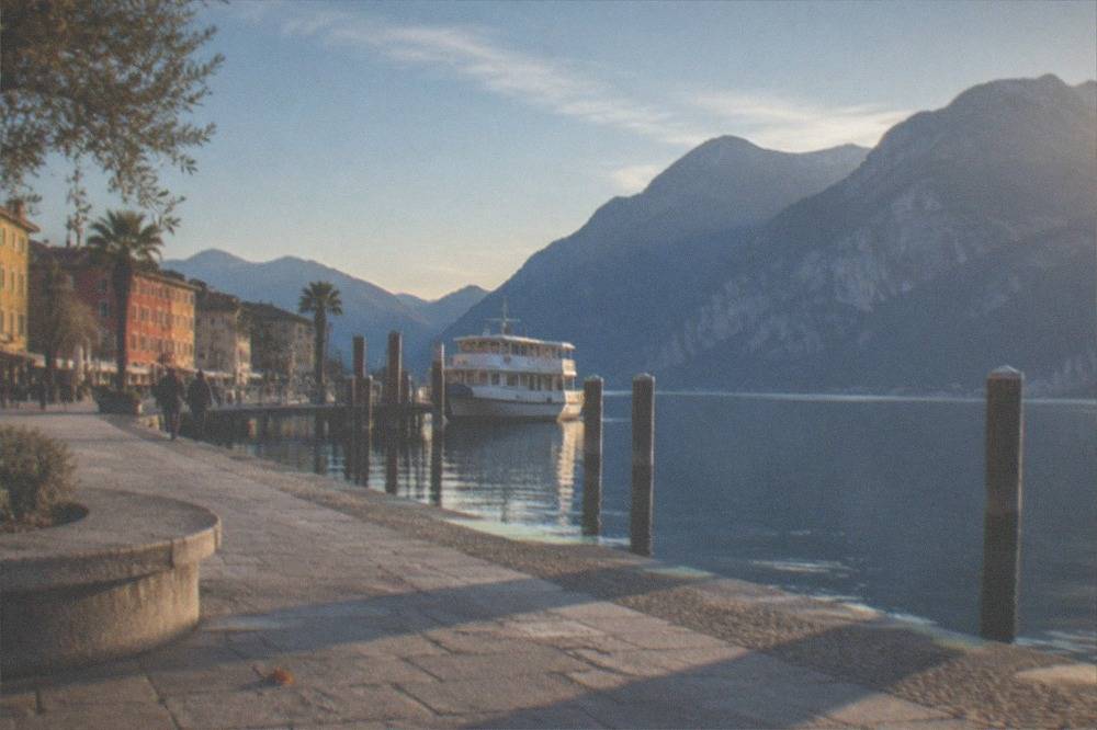 Low winter sun over Lake Garda with long shadows across a lakeside promenade