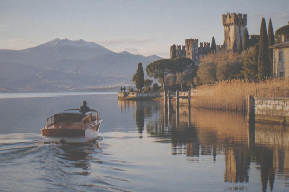 A classic wooden boat gliding over still water near the Sirmione peninsula in winter light