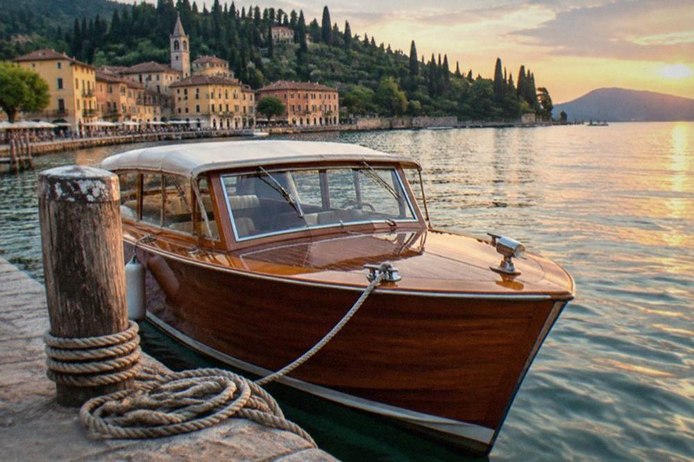 A wooden boat moored at a lakeside town in warm evening light with hills behind