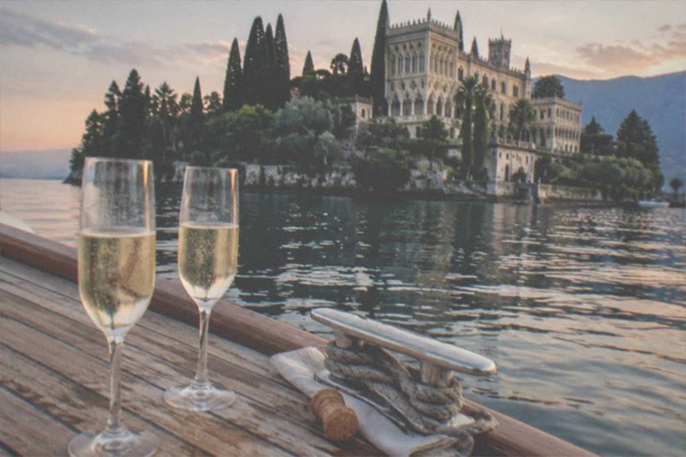 Two glasses of sparkling wine on a boat deck with the lake and evening sky behind