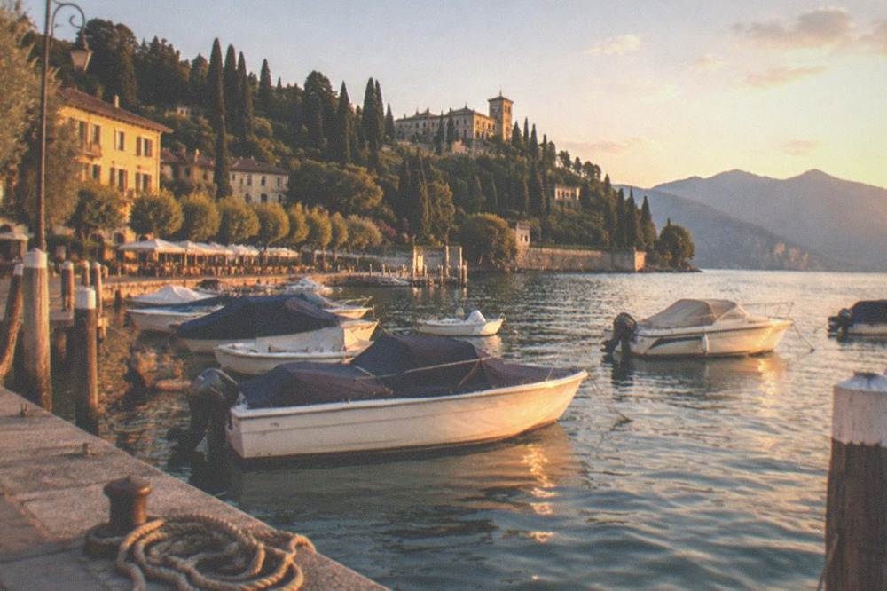 Golden evening light over a quiet Lake Garda harbour with small boats at their moorings