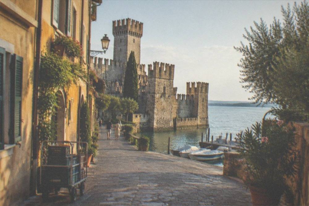 A narrow medieval street in Sirmione's old town with the castle walls rising at the end