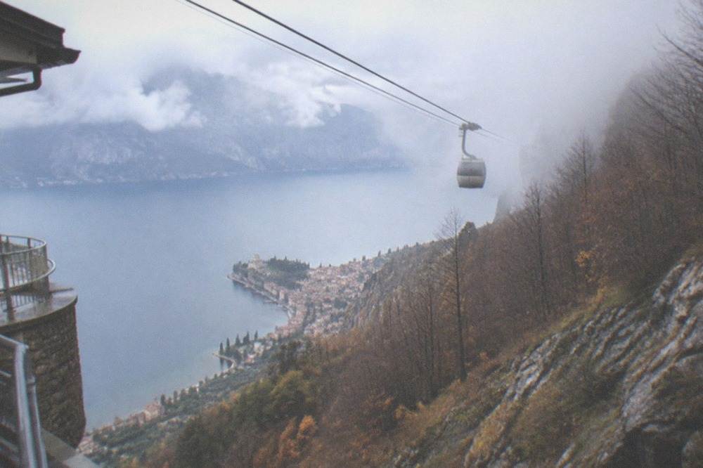 Cable car cables rising into low cloud over the Monte Baldo ridge