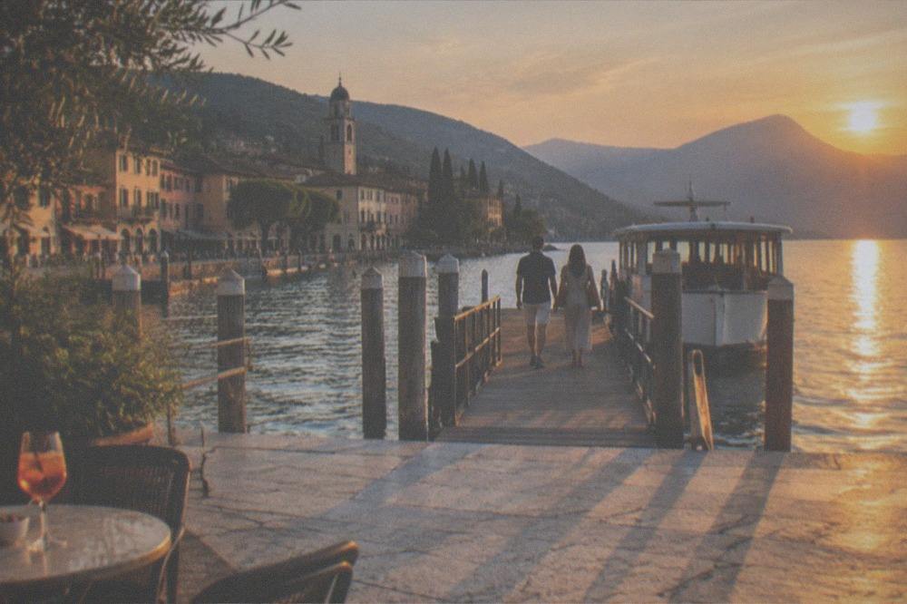 Couple boarding a small tour boat at a wooden pier in late afternoon light
